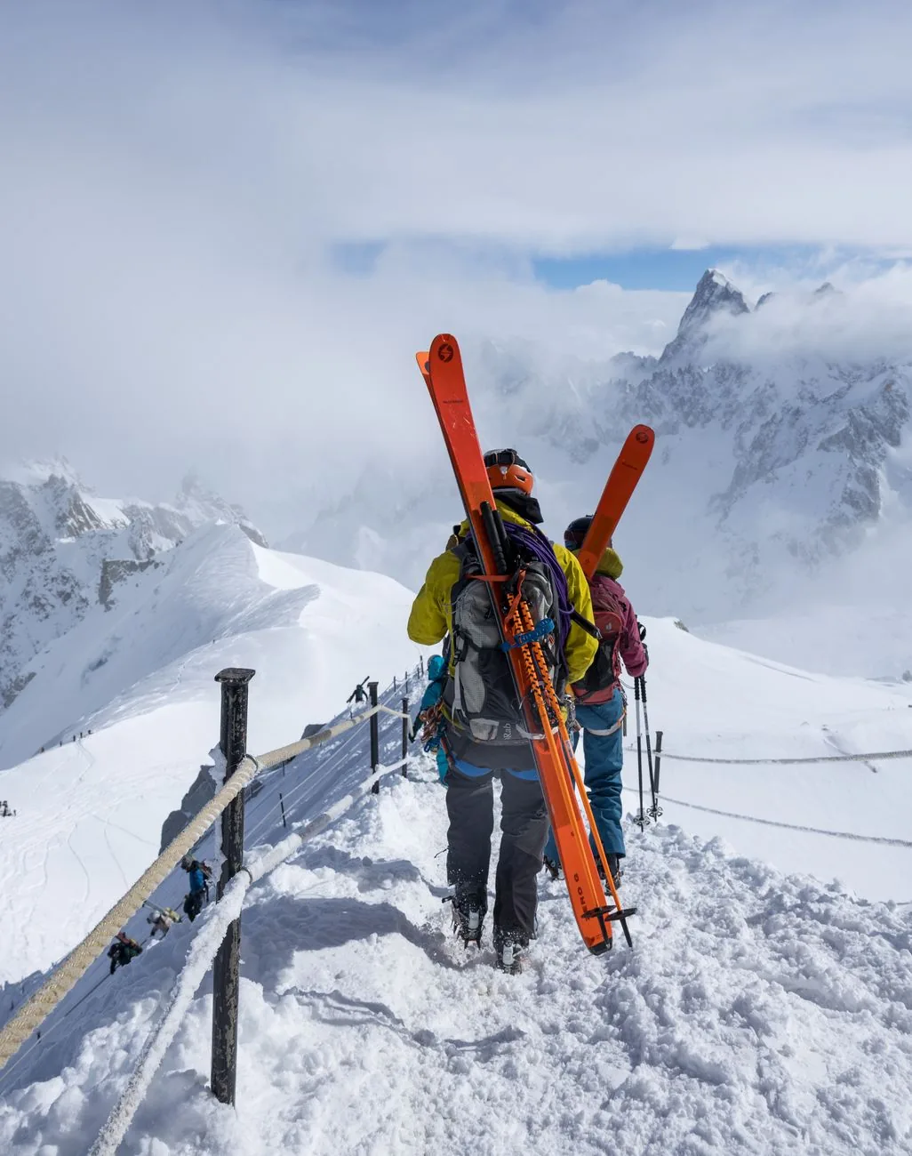 Two people in Vinterra jackets carrying skis