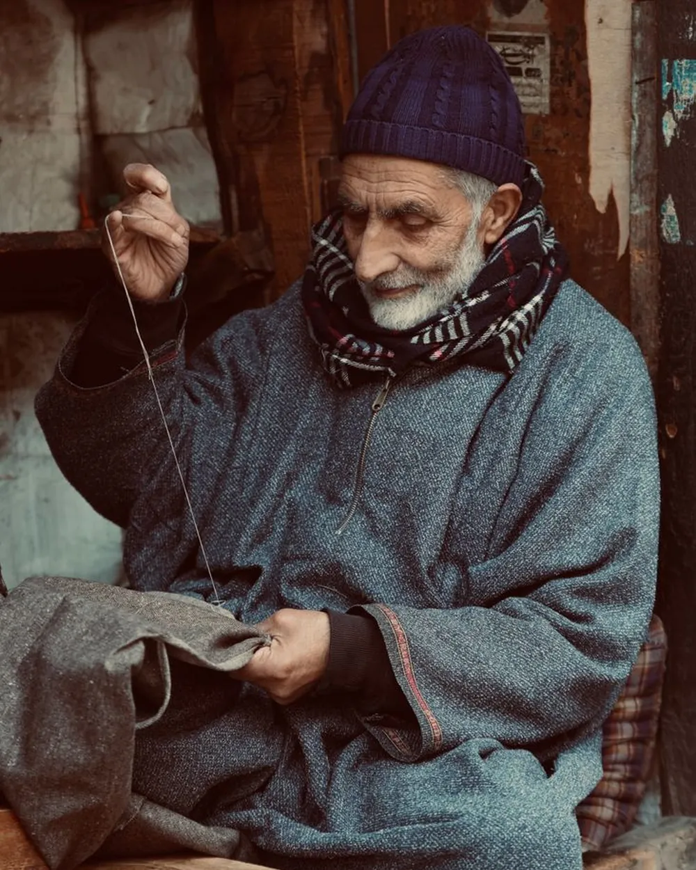 A tailor mending a garment by hand at a sewing machine