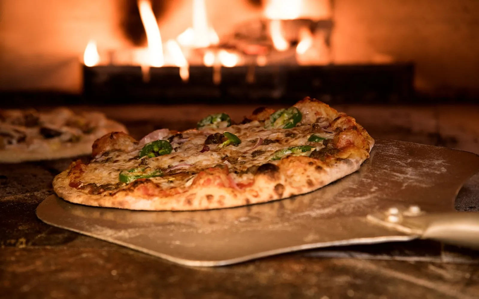 A pizza coming out of the oven on a peel
