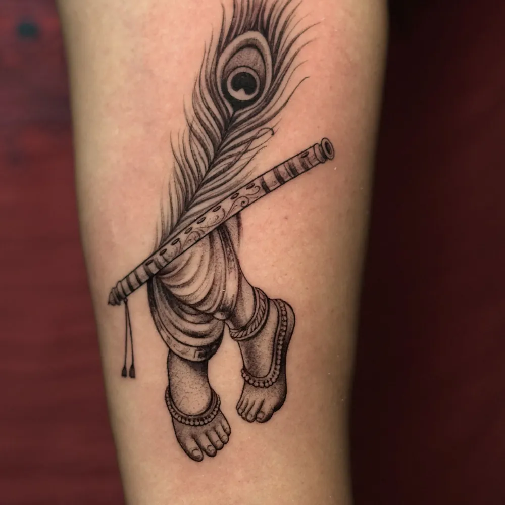 Flute & peacock feather, Realism tattoo on the Forearm by Isha Menon